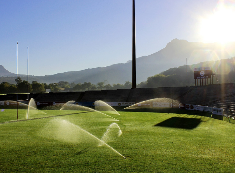 Sports field with irrigation water sprinklers on