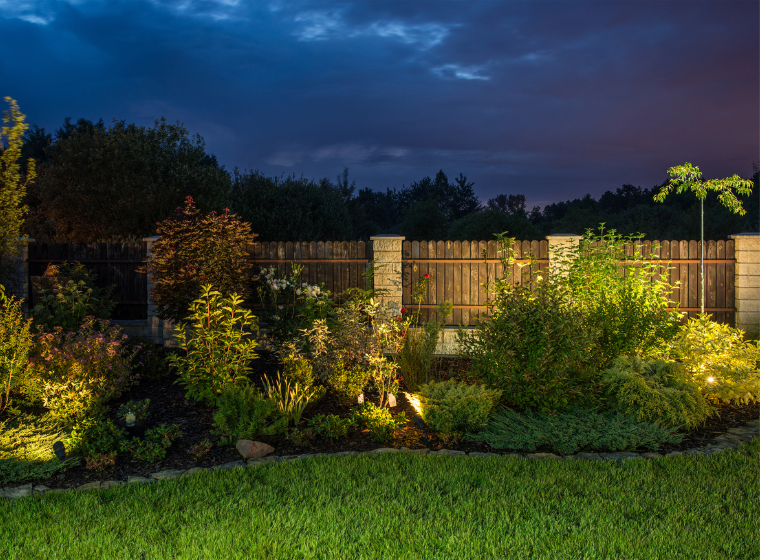 Yard of a home at evening with landscape lighting. Outdoor lighting solutions by Perimeter Landscape OKC.
