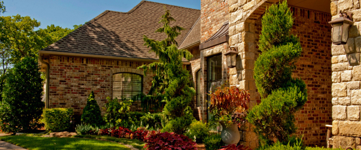 Brick home with trees, shrubs and bushes for landscaping and shade.